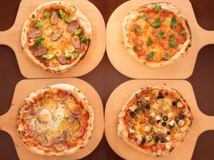 four pizzas sitting on wooden plates on a table at The BREAKFAST HOTEL Fukuoka Tenjin in Fukuoka