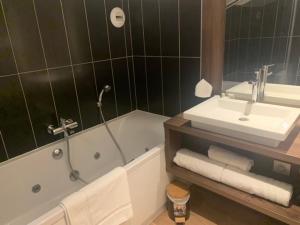 een badkamer met een wastafel, een bad en een wastafel bij Hôtel QUAI33 in Saint-Étienne
