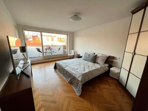 1 dormitorio con cama y ventana grande en Lovely large flat in historic building, balcony, parking, en Praga
