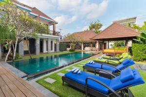a pool with blue lounge chairs next to a house at Villa Bon Bon in Canggu