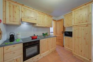 a kitchen with wooden cabinets and a stove top oven at Villa Il Castagno Few Min From Beach - Happy Rentals in Castelveccana