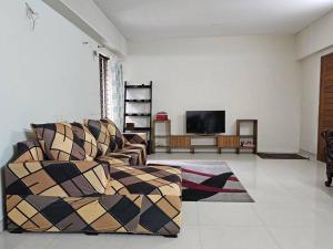 a living room with a couch and a flat screen tv at Vintage GreyRoom - Family Stay in Dhaka