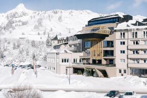 um edifício na neve com uma montanha ao fundo em Hotel Steiner Superior em Obertauern