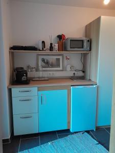a kitchen with blue cabinets and a microwave on a shelf at Dirnböck & Menneweger in Sankt Josef
