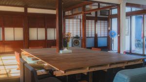 a large wooden table in a room with chairs at ゲストハウス麓〼-Rokumasu in Yokooka