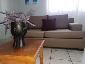 a vase on a coffee table in front of a couch at Άνετο Διαμέρισμα in Artemida