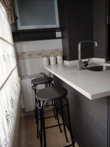 uma cozinha com dois bancos de bar e um lavatório em Precioso Piso+Garaje Zona Sanxenxo Grove Portovono em Pontevedra