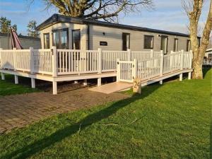 a tiny house with a white fence and a yard at Hafan y Môr Holiday Park in Pwllheli