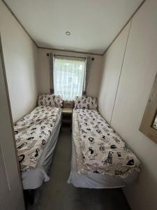 two beds in a small room with a window at Hafan y Môr Holiday Park in Pwllheli
