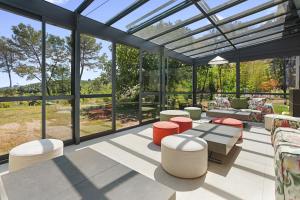 Un invernadero de cristal con una mesa y taburetes. en Villa Nandina, en Trans-en-Provence