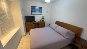 a small bedroom with a bed and a television at Hermoso Condo Frente al Mar in Puerto Vallarta