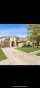 una gran casa de ladrillo con un árbol delante en Kings and Queens luxury home, en Grand Prairie