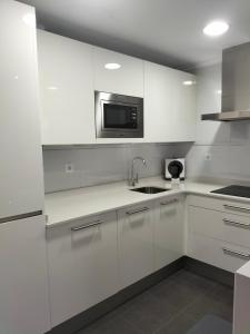 a white kitchen with a sink and a microwave at Apartamento Virgen del Carmen in Santoña