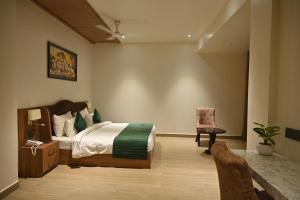 a bedroom with a bed and a desk and a chair at Hotel Gold In Leaf in Alīgarh
