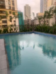 a large blue swimming pool in a city with buildings at Room in Flat with Amazing City and Sea View in Mumbai