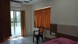 een slaapkamer met een bed, een bureau en een stoel bij SPN Shubam Rooms in Tirunelveli