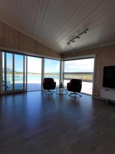 uma sala de estar com duas cadeiras e uma televisão e janelas em Moderne rorbu i Lofoten, Vestvågøy em Gravdal