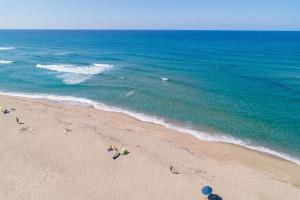 a group of people on a beach near the ocean at ISA-Residence with swimming-pool in Badesi, apartments with air conditioning and private outdoor space in Badesi