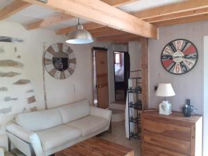 uma sala de estar com um sofá e um relógio na parede em Maison individuelle, La Miloune em Le Val