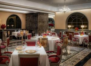 een restaurant met witte tafels en stoelen en een kroonluchter bij Palazzo Versace Macau in Macau