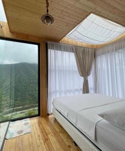 Schlafzimmer mit einem Bett und großen Fenstern in der Unterkunft Pano Blueberry in Namlisevi