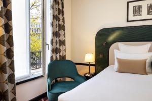 a bedroom with a bed and a chair and a window at Hôtel Aiglon in Paris