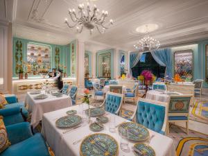 un comedor con mesas, sillas azules y una lámpara de araña en Palazzo Versace Macau en Macao