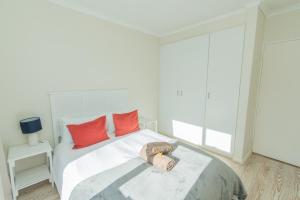 um quarto com uma cama branca e almofadas vermelhas em P7 - Goose Valley - Ocean Views em Plettenberg Bay