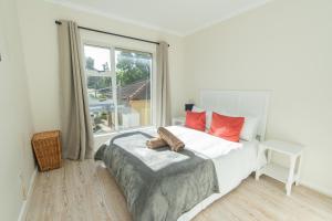 a bedroom with a bed with red pillows and a window at P7 - Goose Valley - Ocean Views in Plettenberg Bay