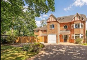 a large brick house with a white garage at The Fairways, St Bernard’s Road in Olton