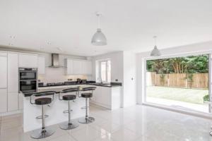 a white kitchen with bar stools and a large window at The Fairways, St Bernard’s Road in Olton