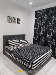 1 dormitorio con 1 cama con edredón blanco y negro en NAURAH HOMESTAY, en Sungai Petani