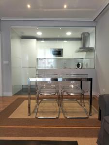 a dining table with two clear chairs in a living room at Apartamento Virgen del Carmen in Santoña