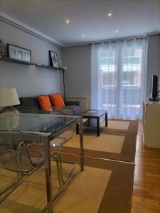 a living room with a glass table and a couch at Apartamento Virgen del Carmen in Santoña