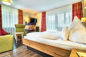 a hotel room with a large bed and a chair at Hotel Das Bayerwald in Lam