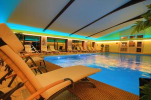 a large swimming pool with chairs and a table at Hotel Das Bayerwald in Lam
