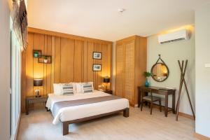 1 dormitorio con cama, mesa y espejo en Synergy Samui en Chaweng