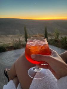 a woman holding a wine glass with the sunset in the background at צימר בוטיק אדלה Zimmer boutique adela in Arad