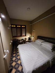 1 dormitorio con 1 cama grande, mesa y sillas en The Grand Bali Hotel en Melaka
