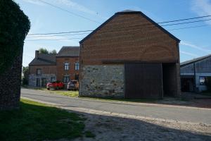 een oud bakstenen gebouw met een garage aan de kant van een weg bij Au Randonneur - B&B in Thuin
