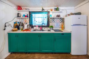 eine Küche mit grünen Schränken und einem weißen Kühlschrank in der Unterkunft Boho House 1 in camp Terme Catez in Čatež ob Savi