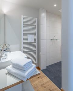a white bathroom with white towels on a counter at Müller! Das Weingut & Weinhotel in Hammelburg