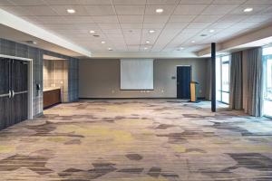 a large meeting room with a projection screen in a building at Courtyard by Marriott Appleton Riverfront in Appleton