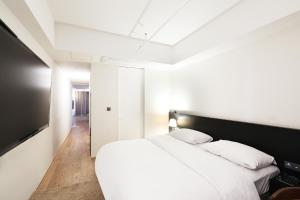 een slaapkamer met een groot wit bed met witte kussens bij Hotel 498 in Incheon