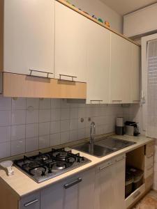 uma cozinha com uma placa de fogão e armários brancos em Comfortable apartament 2 bedroom suitable 2-5 pax em Bolonha