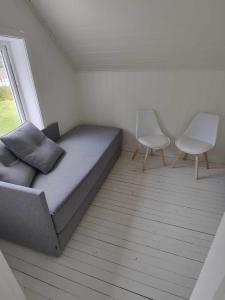 a small bedroom with a bed and two chairs at Koselig hus i det gamle fiskeværet Abelvær in Abelvær