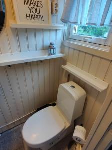 uma casa de banho com um WC e uma placa que diz fazer-te feliz em Koselig hus i det gamle fiskeværet Abelvær em Abelvær