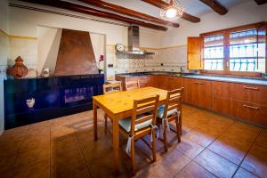 cocina con mesa de madera y sillas en Masia Cal Magi, en Font-Rubí