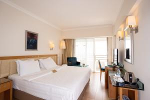 una camera d'albergo con un grande letto bianco e una scrivania di Korumar Hotel Deluxe a Kusadası