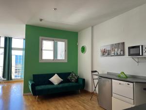 Aparment sierra Guadalupe في مدريد: غرفة معيشة مع أريكة خضراء ومطبخ